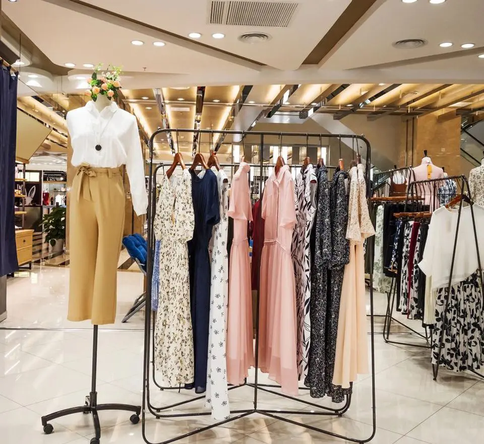 A rack of clothes in a store with several different styles.