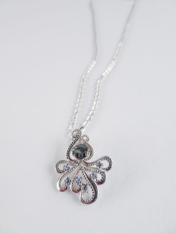 A silver necklace with an octopus pendant on it.