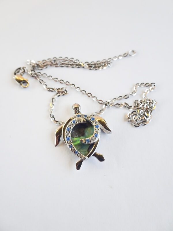 A turtle necklace with green and yellow stones.