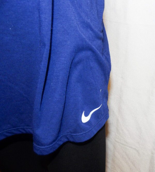 A close up of the sleeve and pocket on a blue nike shirt.