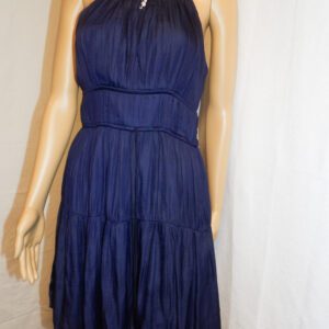 A woman wearing a blue dress standing next to a wall.