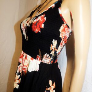 A close up of the waist and bust of a woman wearing a black floral dress.