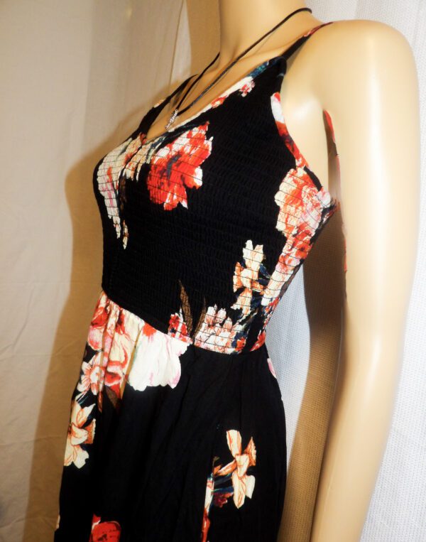 A close up of the waist and bust of a woman wearing a black floral dress.