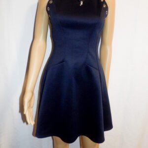 A woman wearing a black dress standing next to a wall.