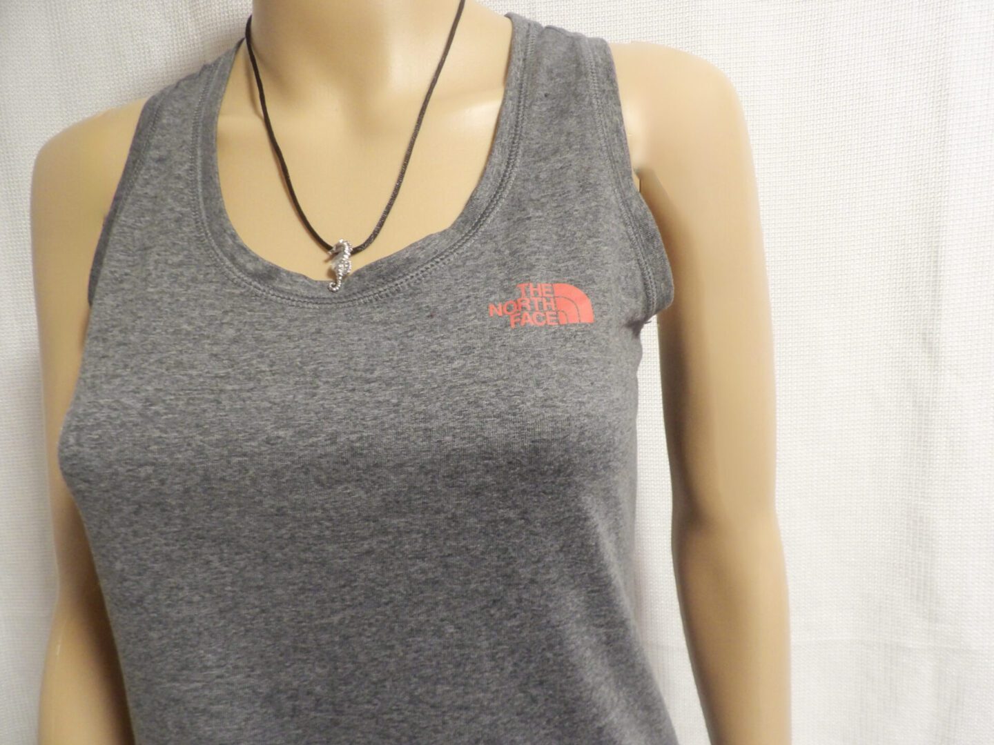 A woman wearing a gray tank top with the north face logo on it.