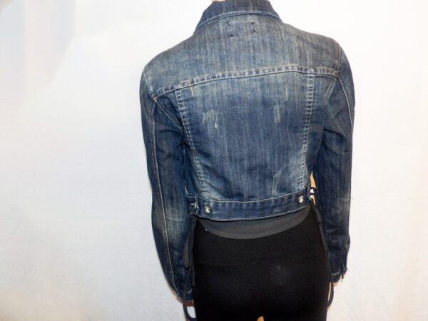 A person wearing a jean jacket and black pants.