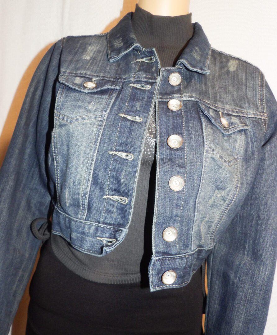 A mannequin wearing a jean jacket with white buttons.