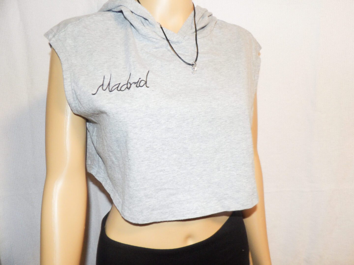 A woman wearing a gray crop top with the name isabel written on it.