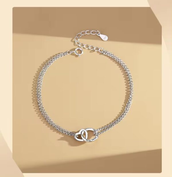 A silver chain bracelet with two hearts on it.