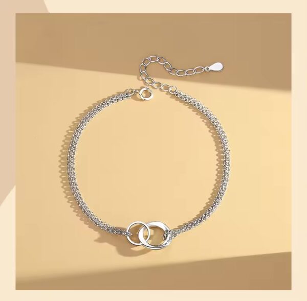 A silver chain with two linked hearts on it.