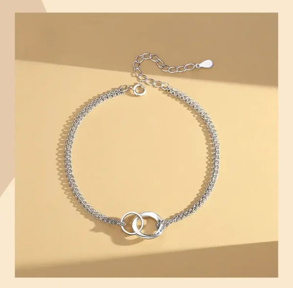 A silver chain bracelet with two interlocking rings.