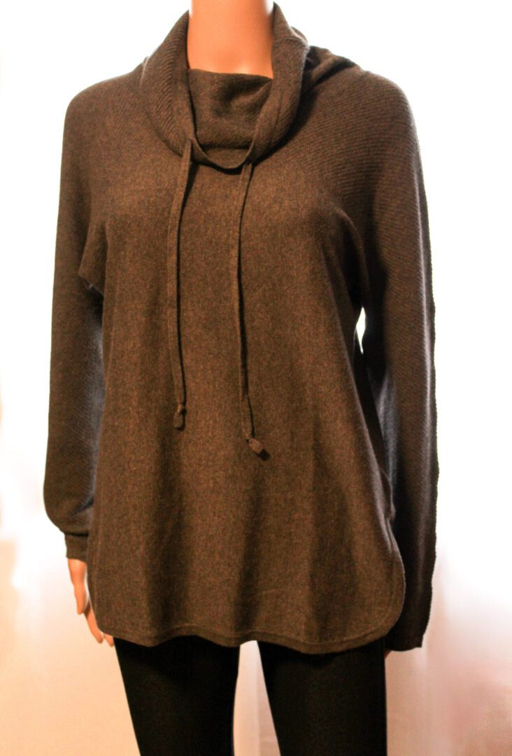 A woman wearing a brown sweater with a black top.