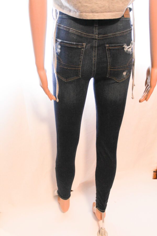 A mannequin wearing jeans and boots with a pair of scissors.