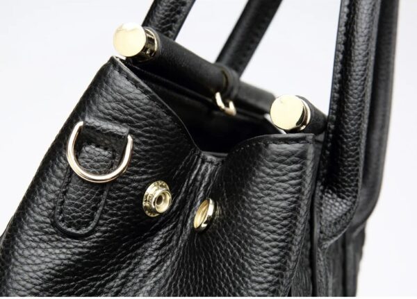 A close up of the handle on a black purse