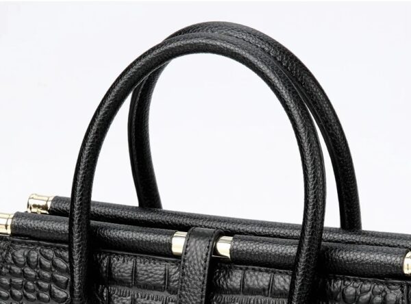 A close up of the handle on a black purse