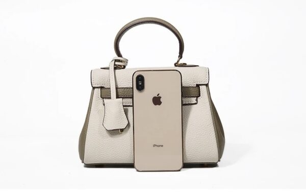 A white purse with an apple phone in front of it.