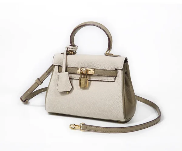 A white purse with a strap and lock on it.