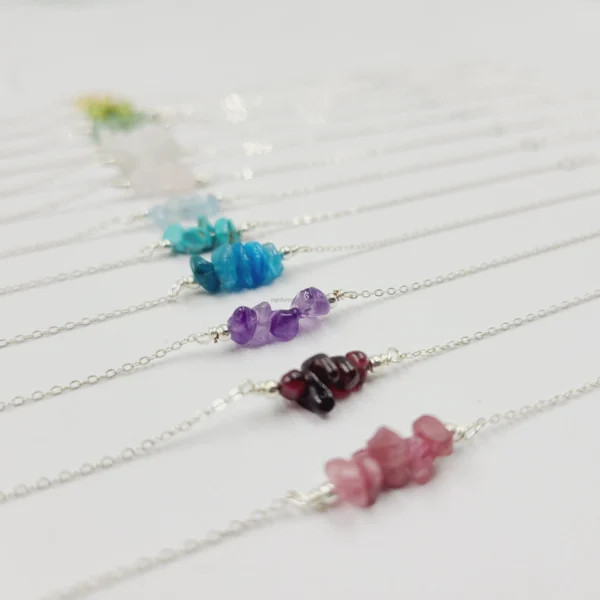 A row of different colored gemstone necklaces on a table.