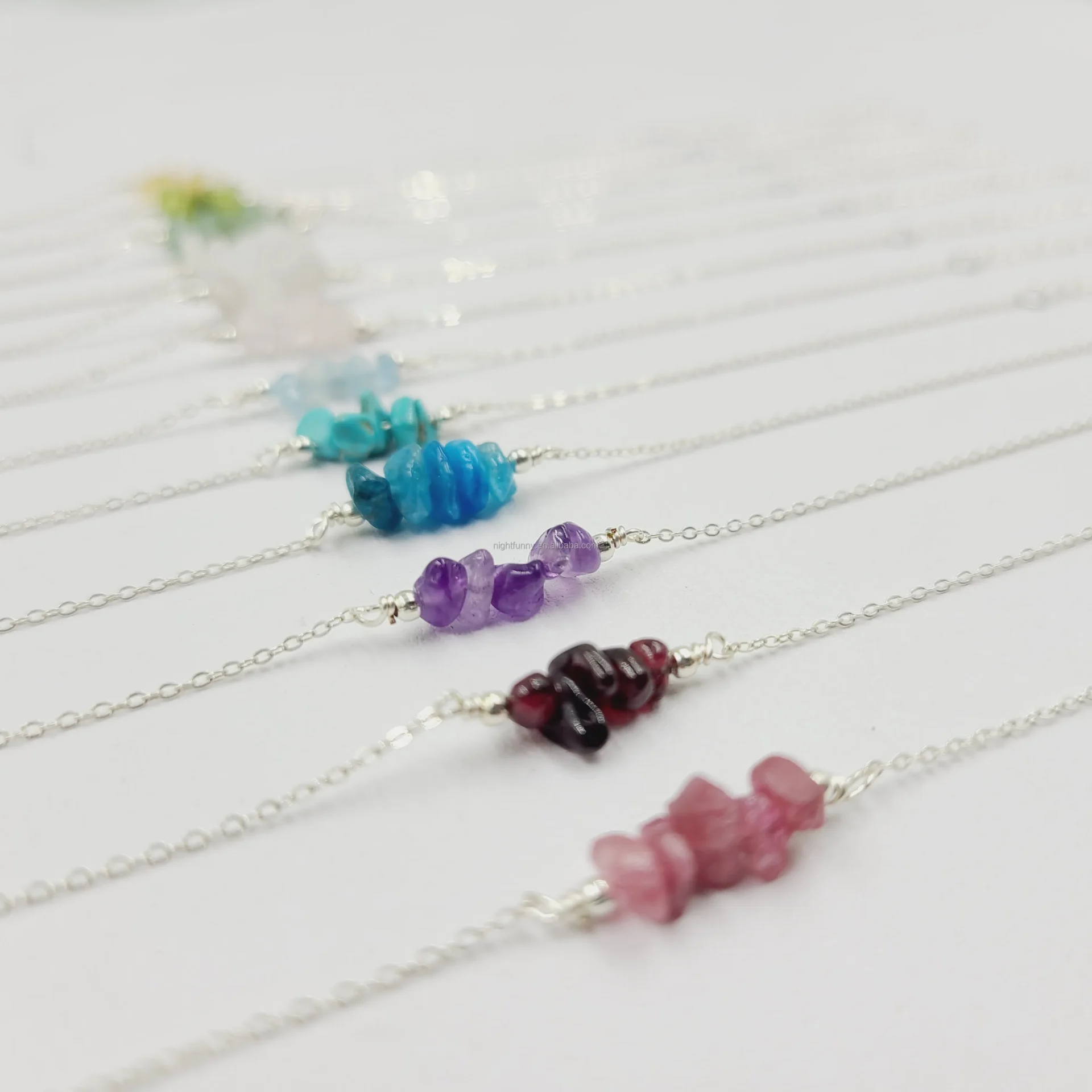 A row of different colored gemstone necklaces on a table.