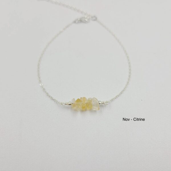 A yellow stone is sitting on top of a silver chain.