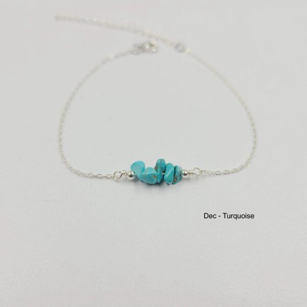 A silver bracelet with turquoise stones on it.