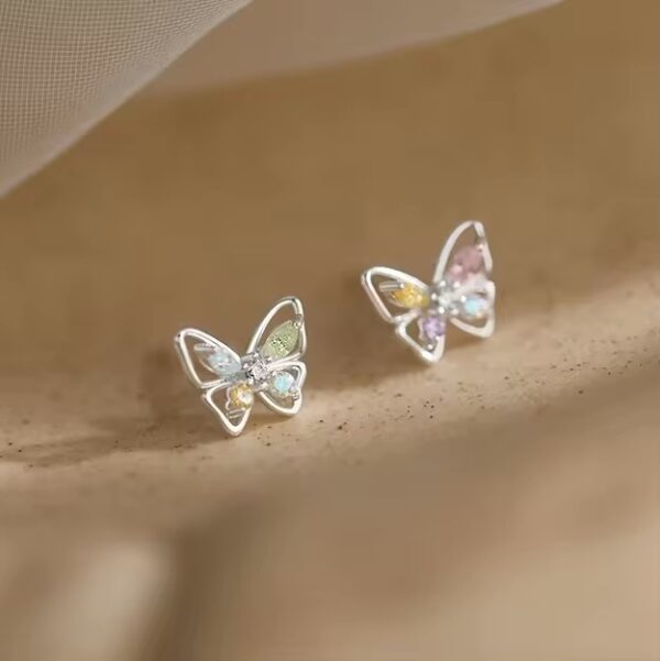 A pair of butterfly earrings sitting on top of a brown cloth.