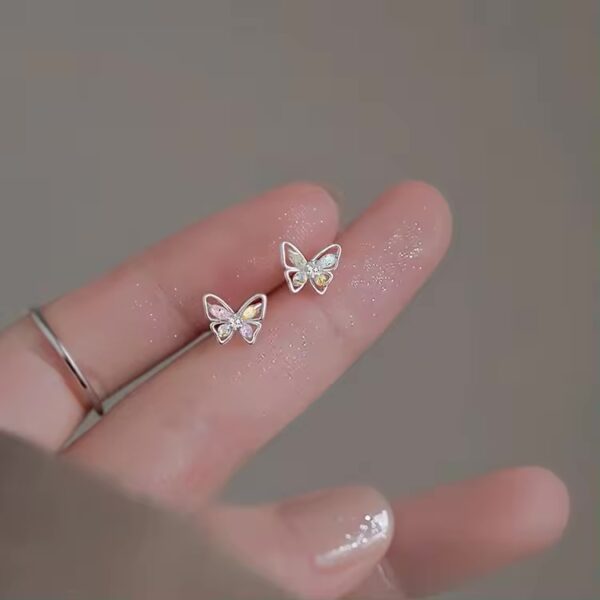 A person holding onto some small butterfly earrings