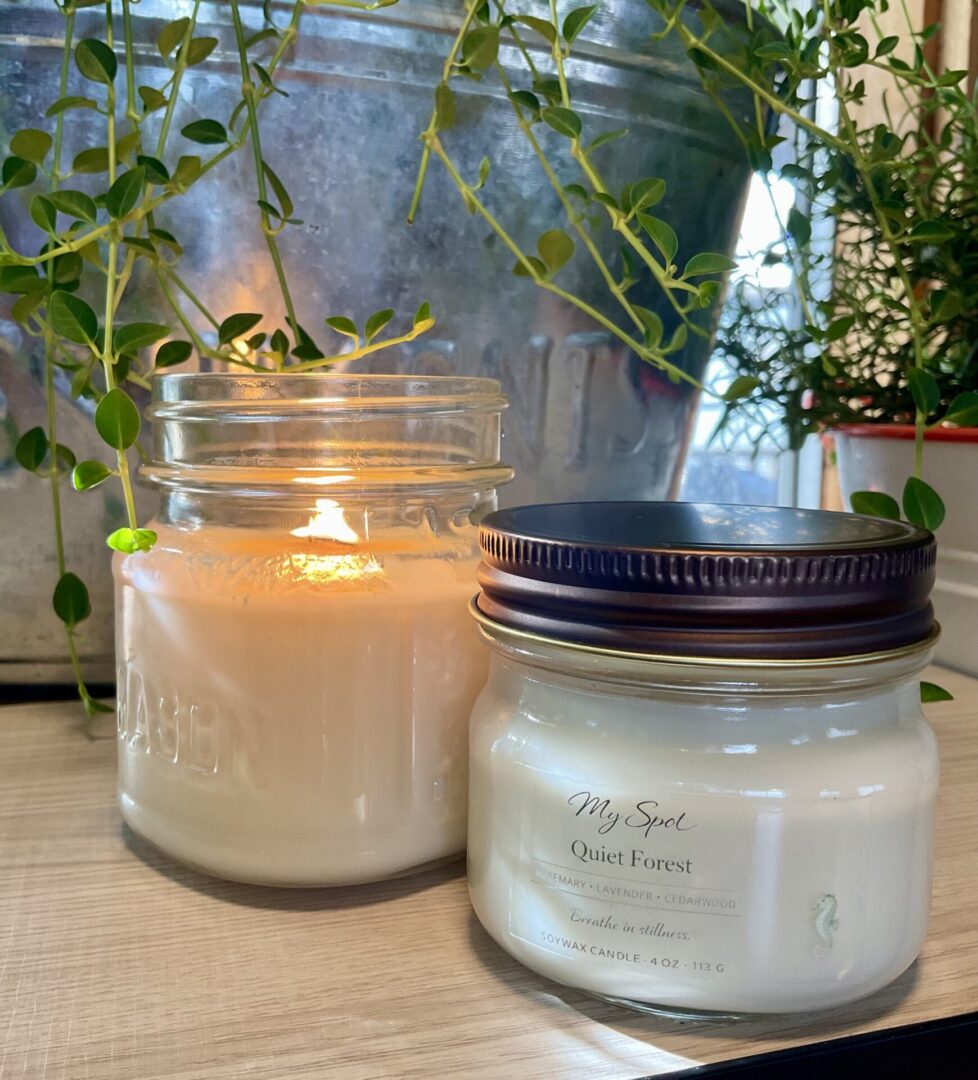 handmade soy candle burning in glass jar with natural greenery cozy warm setting
